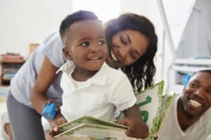 Family With Young Children Reading Book In Playroom Together