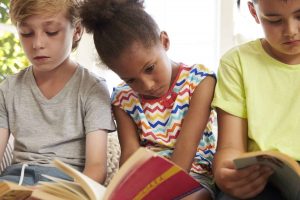 Close Up Of Children Reading On Window Seat Close Up Of Children Reading On Window Seat